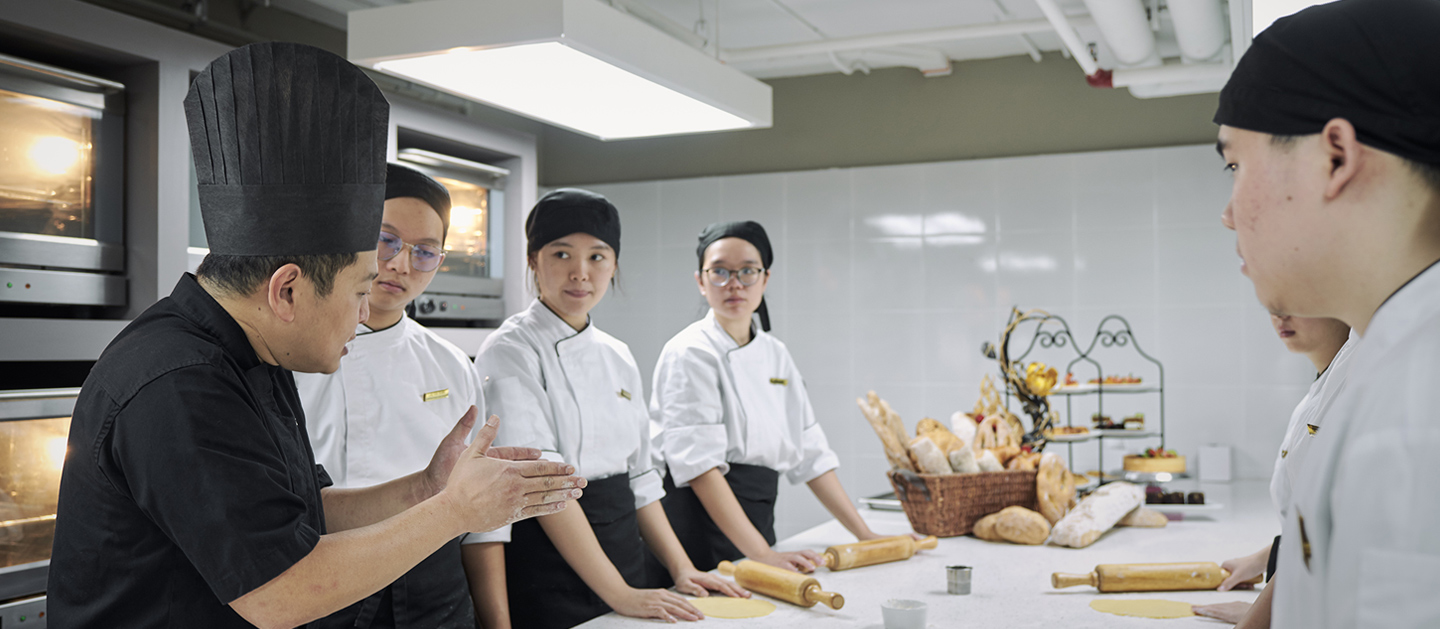 A lecturer is teaching students on pastry and bakery.