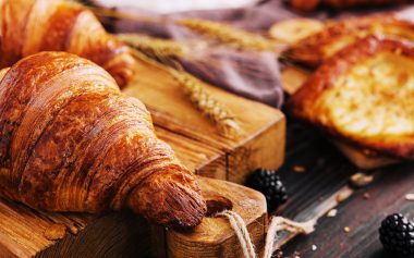 Board with tasty croissants and pastries on table